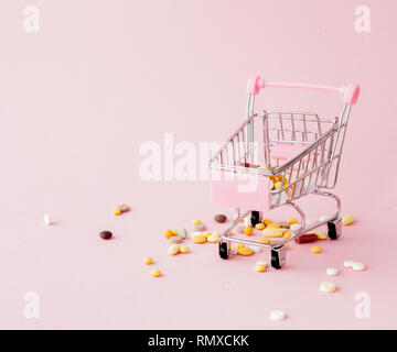 Panier du supermarché plein de pilules et drogues sur un fond rose. Les achats de médicaments, l'achat sur Internet. Télévision Banque D'Images