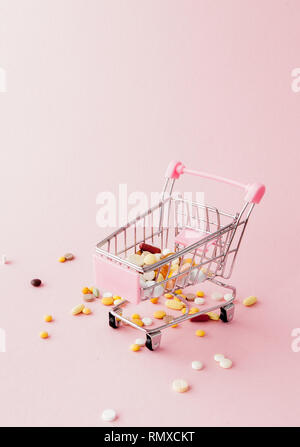 Panier du supermarché plein de pilules et drogues sur un fond rose. Les achats de médicaments, l'achat sur Internet. Télévision Banque D'Images