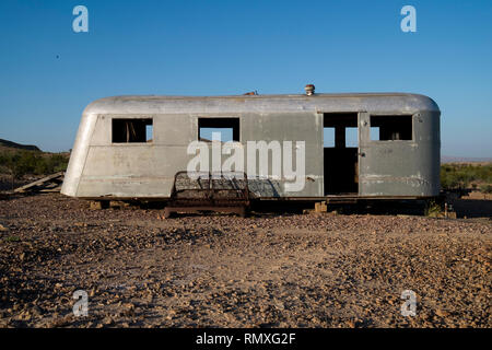 Un vieux, abandonné et ruiné vintage Airstream remorque avec un canapé-lit rouillé à l'extérieur. Dans le désert de l'ouest du Texas. Banque D'Images