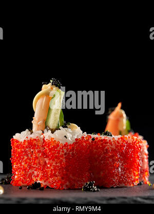 Couvert de sushi volcan oeufs de poisson volant rouge. Uramaki japonais rouleaux de riz aux crevettes, concombre et surmonté de sauce et black caviar. Banque D'Images