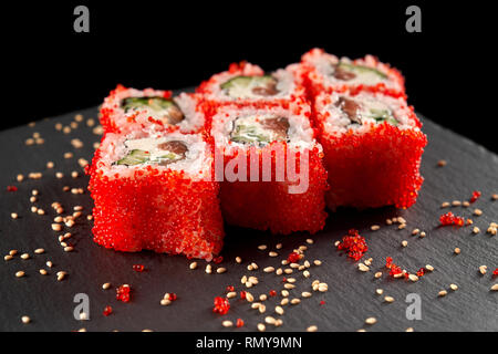 Rouleau de Philadelphie Uramaki rempli de saumon, concombre, avocat et fromage à la crème. Rouleaux Philly recouvert d'oeufs de poisson volant rouge. Banque D'Images