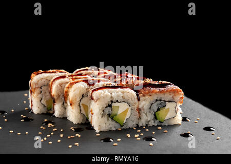 California rolls dans menu sushi. Délicieux sushis rempli de fromage à la crème, d'avocat et de l'anguille fumée. Garni de sauce unagi Uramaki, décoré avec du sésame. Banque D'Images