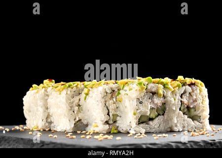 Vue avant du délicieux rouleaux uramaki rempli de concombre, anguille fumé et fromage à la crème. Décorées avec du sésame, présenté sur la plaque d'ardoise. Banque D'Images
