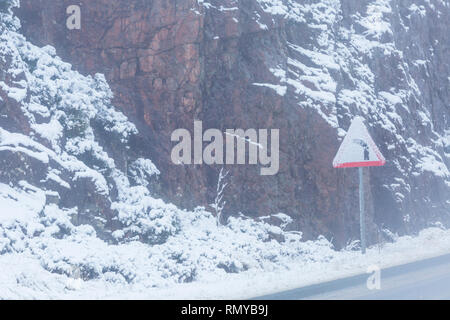Plier au panneau de gauche dans la neige sur la route A82 sur un froid matin d'hiver à Rannoch Moor, Argyll, Écosse en janvier - triangle de signalisation de route triangulaire Banque D'Images