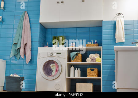 Salle de bains moderne avec lave-linge blanc et carreaux bleu