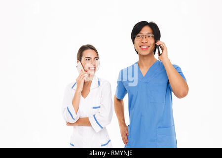 Couple Smiling doctors en uniforme isolés sur fond blanc, talking on mobile phone Banque D'Images