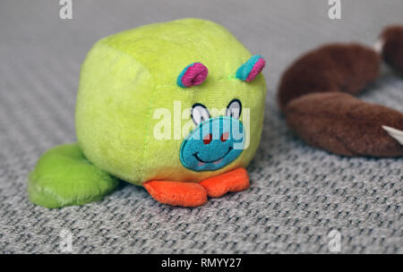 Jouets pour chiens colorés sur une moquette grise. Les jouets en peluche sont marron et vert saucisses petit monstre jouet. Les jouets colorés et mignons. Photo gros plan. Banque D'Images