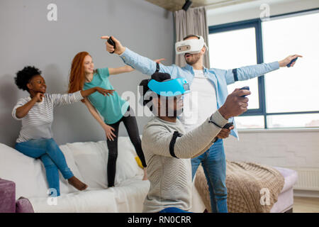 Les étudiants internationaux au repos avec divers lunettes de réalité virtuelle d'une maison, deux jeunes hommes d'hôtesse filles interracial Banque D'Images