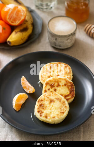 Petit déjeuner végétarien de quark des crêpes au miel, de fruits et de café avec du lait. De style rustique, selective focus. Banque D'Images