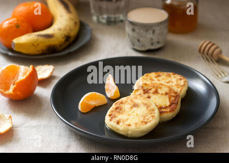 Petit déjeuner végétarien de quark des crêpes au miel, de fruits et de café avec du lait. De style rustique, selective focus. Banque D'Images
