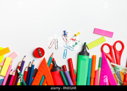 Un assortiment de fournitures scolaires, y compris des stylos, crayons, ciseaux, colle et d'une règle, sur un fond blanc Banque D'Images