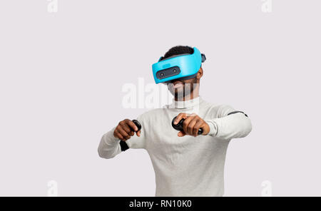 Les barbus à peau sombre modèle masculin en casque de réalité virtuelle à jouer au tennis dans la réalité augmentée. L'avenir. La future technologie concept. Isolé sur Banque D'Images
