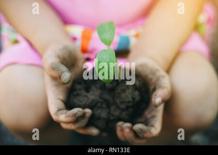 Cute kid planter un arbre pour aider à prévenir le réchauffement ou le changement climatique et sauver la terre. Photo de concept de la Journée de la Terre Mère pour encourager Banque D'Images