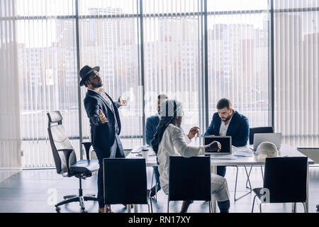 Les hommes d'entreprises multiculturelles des réunions et l'examen avec des graphiques et des tableaux et montrant des résultats positifs en utilisant comme fond Banque D'Images