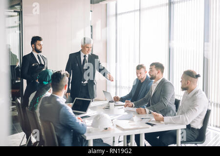 L'équipe diversifiée d'âge moyen des mâles multiethnique, conduisant les investisseurs par des cadres supérieurs expérimentés, Directeur de la coopération sur le développement des investissements communs proj Banque D'Images