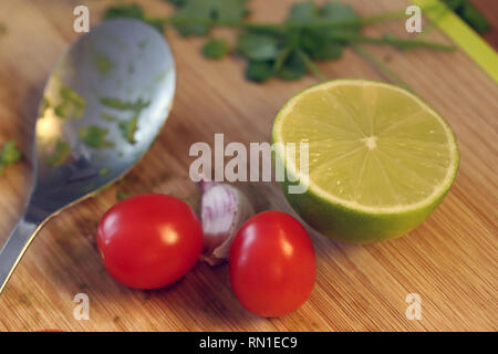 Processus de fabrication de la guacamole - Mexican salsa aux avocats. Sur cette photo vous pouvez voir certains de la guacamole ingrédients sur une planche à découper. Photo gros plan. Banque D'Images