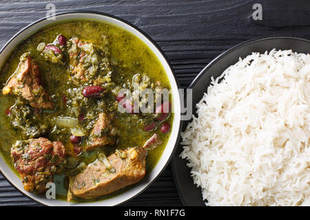 Alimentaire Nationale perse ragoût de viande aux herbes et les haricots close-up dans un bol servi avec riz vapeur sur la table supérieure horizontale. Vue de dessus Banque D'Images