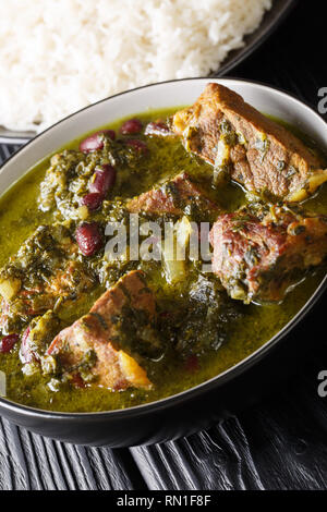 Alimentaire Nationale perse ragoût de viande aux herbes et les haricots close-up dans un bol servi avec riz vapeur verticale sur la table. Banque D'Images