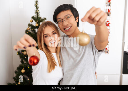 Happy young couple debout à l'arbre de Noël à la maison, la célébration de Banque D'Images