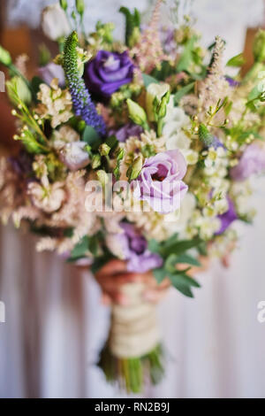 Belle jeune mariée en robe blanche holding bouquet de mariage, bouquet de mariée rose de spray crème, mauve, violet Memory Lane eustoma, eucalyptus . Banque D'Images