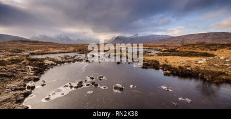 La glace d'hiver manteaux Lochan na h-Achlaise Lake sur la grande tourbière de lande de Rannoch Moor, avec les sommets enneigés des montagnes noires dans la distance. Banque D'Images