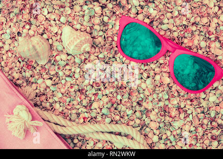 Scène de plage. Sac de plage et lunettes de soleil couché sur coquilles coquina mer Banque D'Images