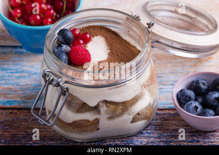 Tiramisu dessert savoureux dans un bocal en verre sur la table de couleurs Banque D'Images