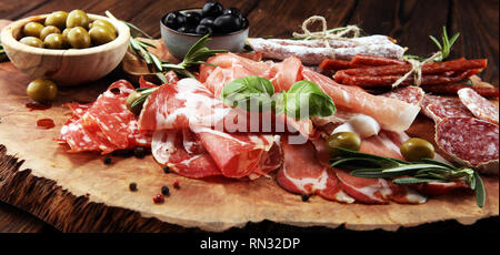 Planche à découper en marbre avec jambon, bacon, salami et saucisses sur fond de bois. Hors-d'assiette de viande et les olives Banque D'Images