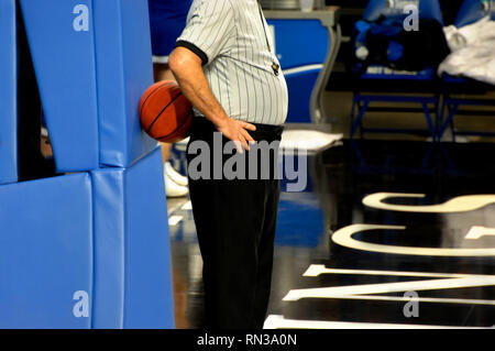 Arbitre pendant un délai de basket-ball, s'appuie contre l'objectif et utilise le basket-ball pour un dossier. Banque D'Images