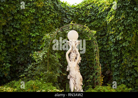 Sculpture d'une fille avec un panier dans un parc public fond vert Banque D'Images