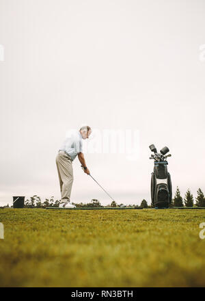 Low angle view of senior man at un practice à jouer au golf et pratiquer son swing. Toute la longueur de senior male golfer pratiquant à golf. Banque D'Images