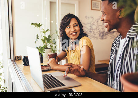 Deux médias sociaux jusqu'à une réunion d'influenceurs et de discuter sur leur gâteau de nouveau contenu. L'homme et la femme assis à table de café avec ordinateur portable. Banque D'Images