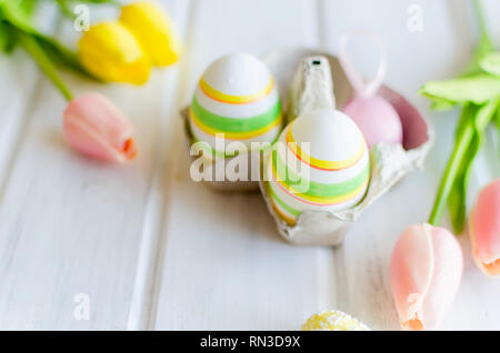 Tulipes jaunes, ginger cookies, des brindilles de saule, de la décoration des oeufs dans un bac blanc disposés sur une vieille table en bois, vacances de Pâques, arrière-plan avec des bonbons, fl Banque D'Images