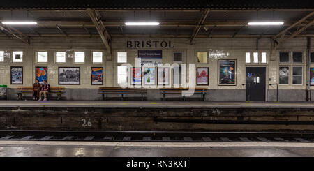 Bristol, Angleterre - le 12 janvier 2019 : un couple de banlieue s'asseoir sur un banc de la plate-forme en attente d'un train à Bristol la gare de Temple Meads. Banque D'Images