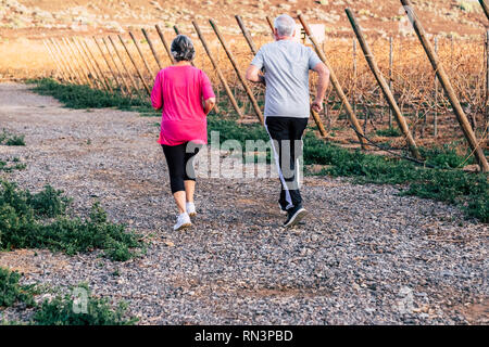 Personnes âgées L'activité sportive avec quelques cheveux blancs adultes fonctionnant dans l'air extérieur côté pays vignoble lieu en été - style de vie sain et de la course à domicile. Banque D'Images