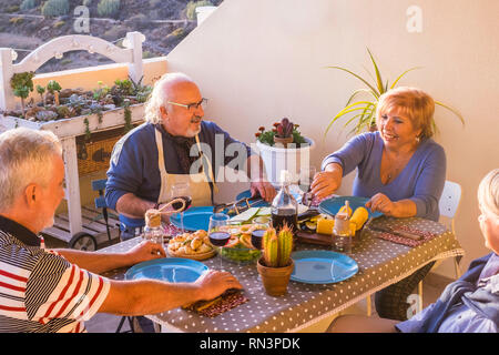 Groupe de deux couples adultes caucasiens personnes manger ensemble en plein air la terrasse à la maison s'amusant - l'amitié et de travail de l'après vie nice - smi Banque D'Images