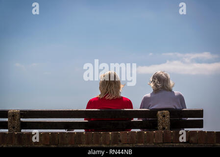 Deux femmes, personnes âgées et d'âge moyen de la mère fille assise sur un banc et regarder la mer, Littlehampton, West Sussex, England, UK Banque D'Images