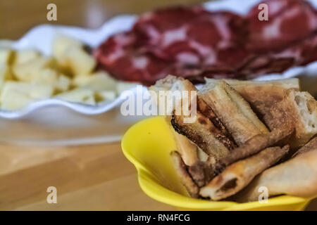 Assiette de viande séchée coppa et fromage accompagné de pains plats mis en place sur la table à dîner à la maison d'une famille à Rome, Italie Banque D'Images