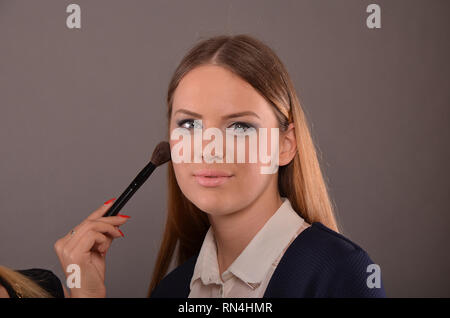 Mignon, jeune blue eyed blende girl posing in studio pendant un miroir Banque D'Images