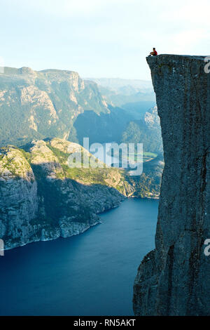 Un homme seul est situé au-dessus de la Pulpit Rock / Preikestolen ou Prekestolen surplombant Lysefjord en Norvège Banque D'Images