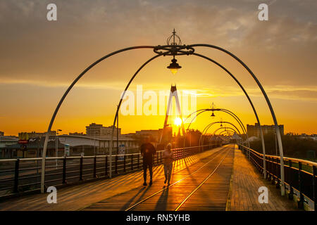 Southport, Merseyside. 17 Février, 2019. Météo britannique. Froid, lumineux ensoleillé de commencer la journée avec un ciel clair. Après une starttemperatures froide devraient augmenter à un unseasonal 14C pendant la journée. La Grande-Bretagne pourrait être définie pour son jour de février le plus chaud si une poussée d'air chaud arrive la semaine prochaine, un prévisionniste des revendications. La journée la plus chaude de ce mois-ci sur fiche est 19.7C. Un marcheur sur le site de la jetée de Southport, la plus ancienne jetée de fer dans le pays qui a été debout pendant plus de 150 ans et est de la ville est grand héritage de l'ère victorienne. Indicateur/AlamyLiveNews Crédit : Banque D'Images