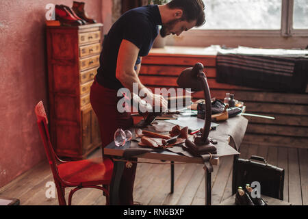 Jeunes talents shoemaker le brossage des chaussures, vue latérale photo. Banque D'Images