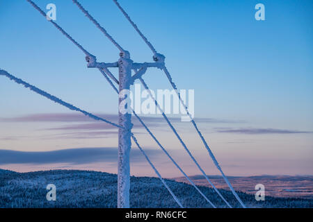 Le gel et la neige a couvert les lignes électriques pendant hiver très froid contre le ciel en Finlande Banque D'Images