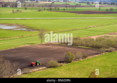 Vue rurale avec un tracteur semé dans un champ au printemps Banque D'Images