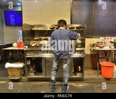 Un ouvrier manipule des pots d'argile cuits sur un poêle à terrasse à l'extérieur d'un restaurant Cha chaan teng, Hong Kong. Banque D'Images