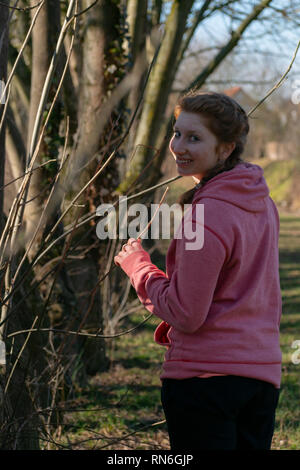 Donner un modèle doux sourire en un regard derrière tourné dans le parc de Lichtenbroich Dusseldorf, Allemagne Banque D'Images