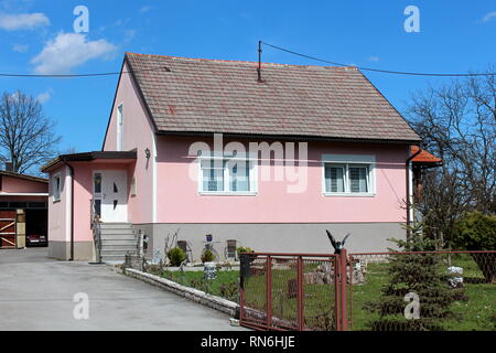 Complètement rénové petite maison de famille de banlieue avec nouvelle façade et fenêtres entourées d'herbe et de décorations dans l'avant avec entrée à côté Banque D'Images