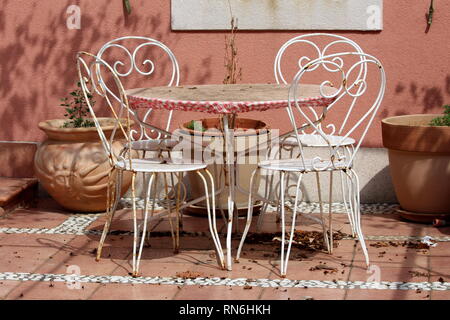Cute vintage retro metal frame outdoor table et chaises blanches en face de mur de la maison avec de grands pots de fleurs en céramique sur des dalles en pierre rez-de-jardin