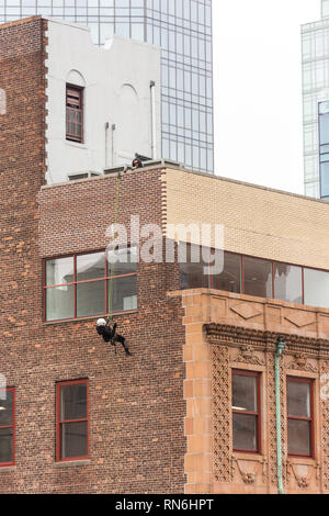 Ingénieur industriel descendre en rappel le long du côté d'un immeuble sur l'inspection des structures, New York City, USA Banque D'Images