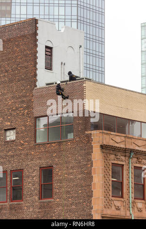 Ingénieur industriel descendre en rappel le long du côté d'un immeuble sur l'inspection des structures, New York City, USA Banque D'Images